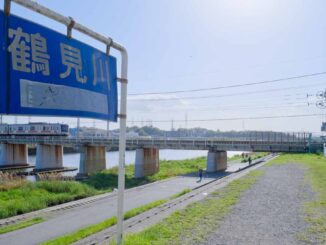鶴見川の看板と東横線の電車
