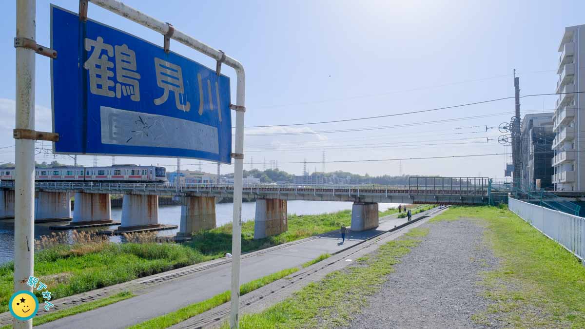 鶴見川の看板と東横線の電車