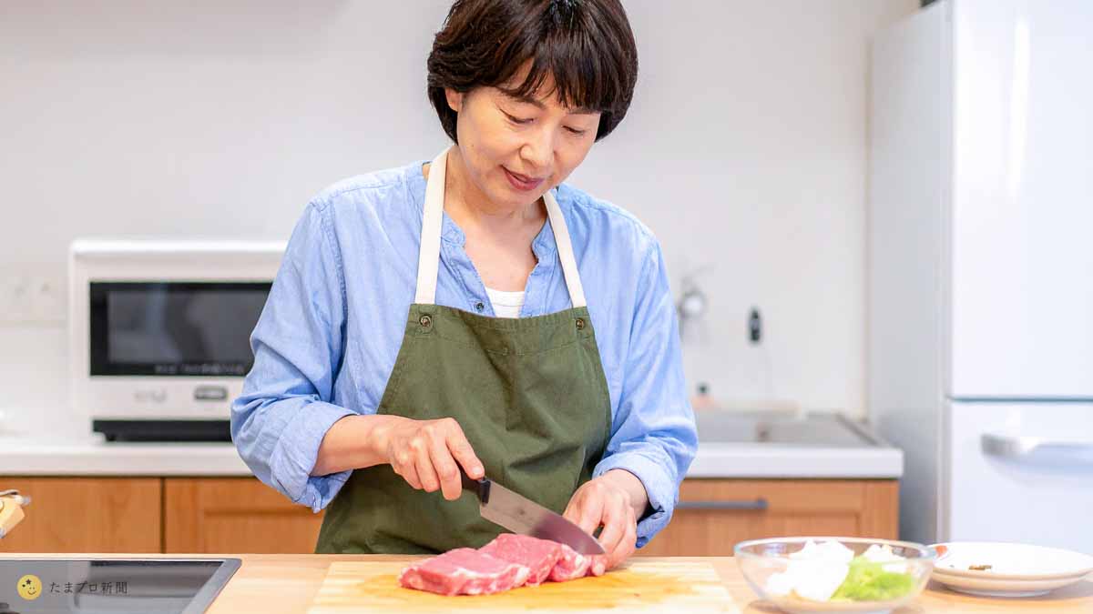母親が台所で肉をカット