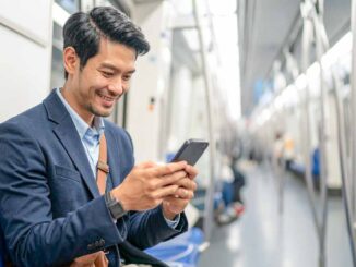 ビジネスパーソンが通勤電車でスマホを見てる