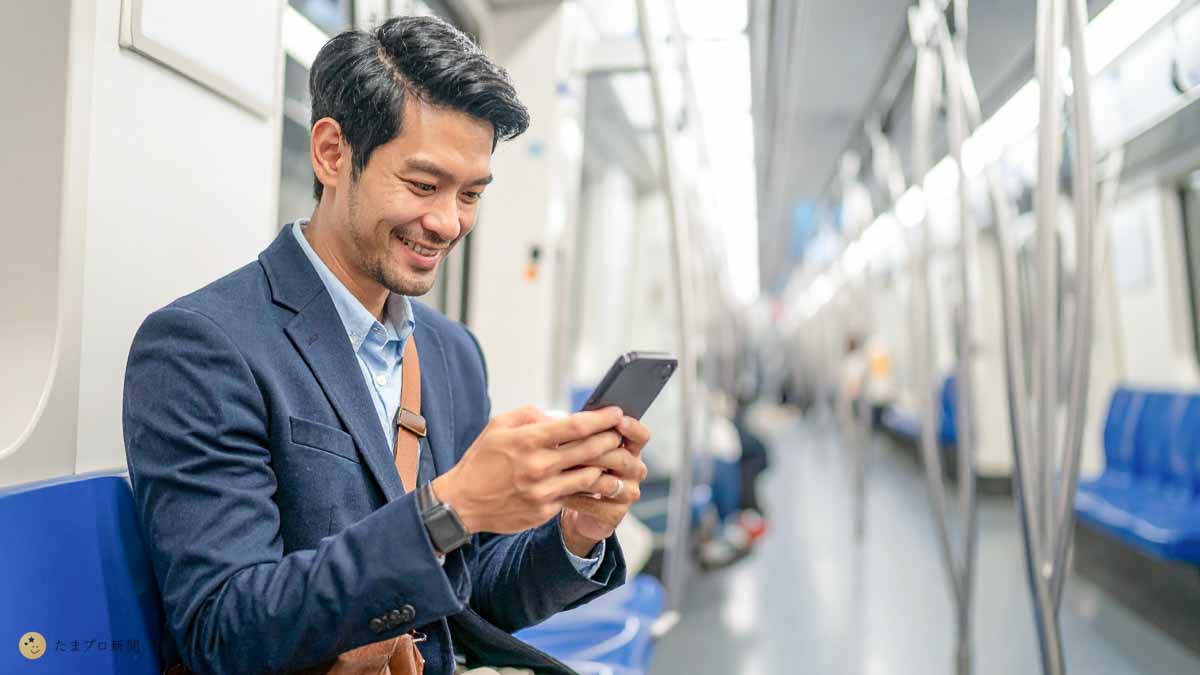 ビジネスパーソンが通勤電車でスマホを見てる