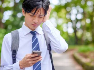 スマホを見て悩む男子高生