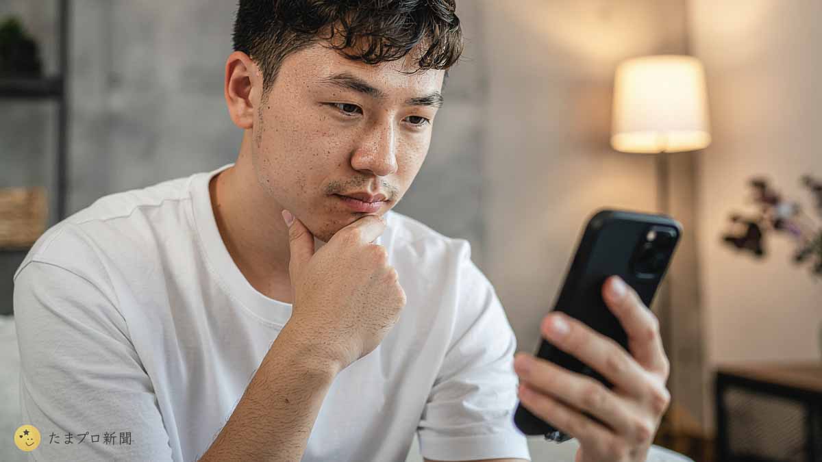 スマホを見て悩む青年