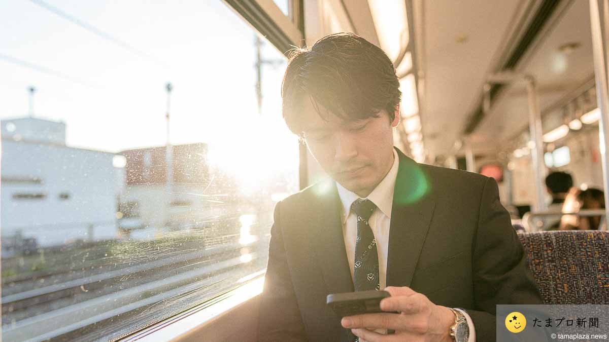 電車の中でスマホで記事を読む人